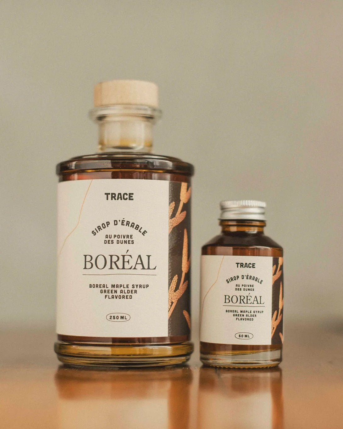Une bouteille de deux formats différents du sirop d'érable boréal au poivre des dunes de l'entreprise Trace.